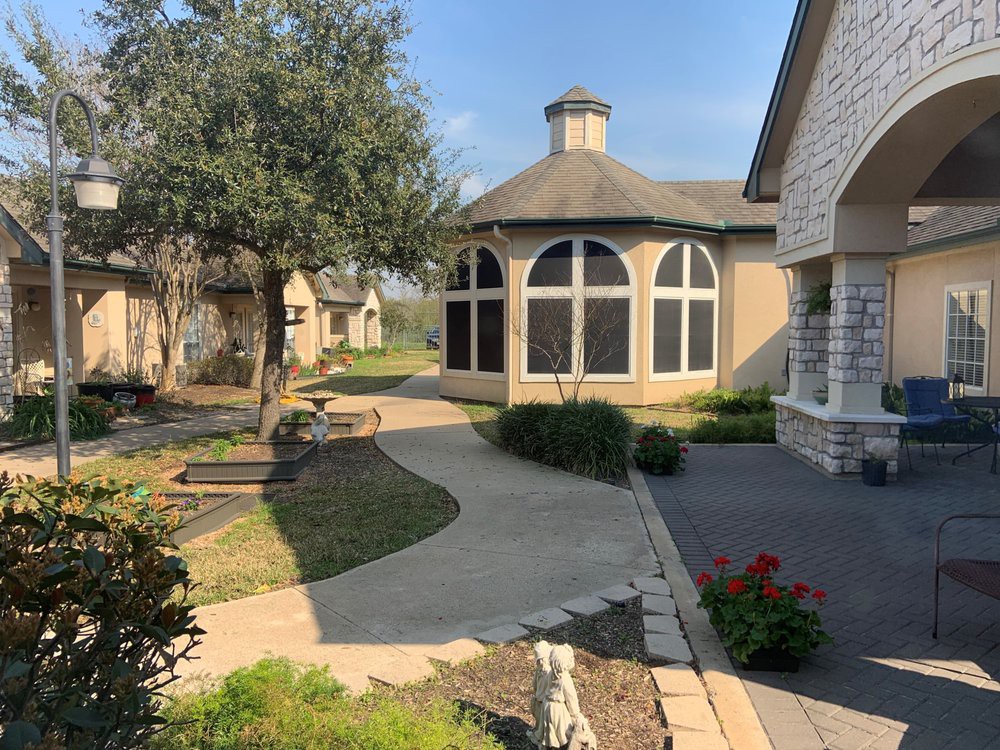 A scenic view of a courtyard with a curved pathway, surrounded by trees and well-maintained landscaping.