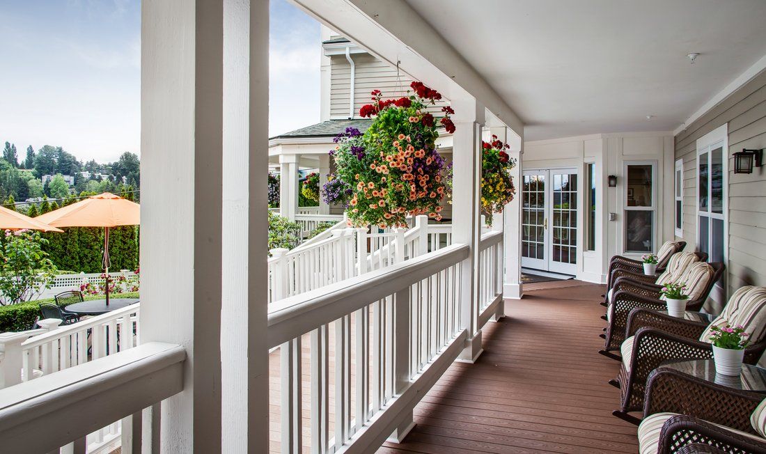 A charming porch with hanging flower baskets, featuring a well-maintained wooden deck and white railing.