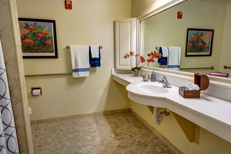 A well-organized bathroom with a large mirror, sink, and neatly arranged towels and decor.