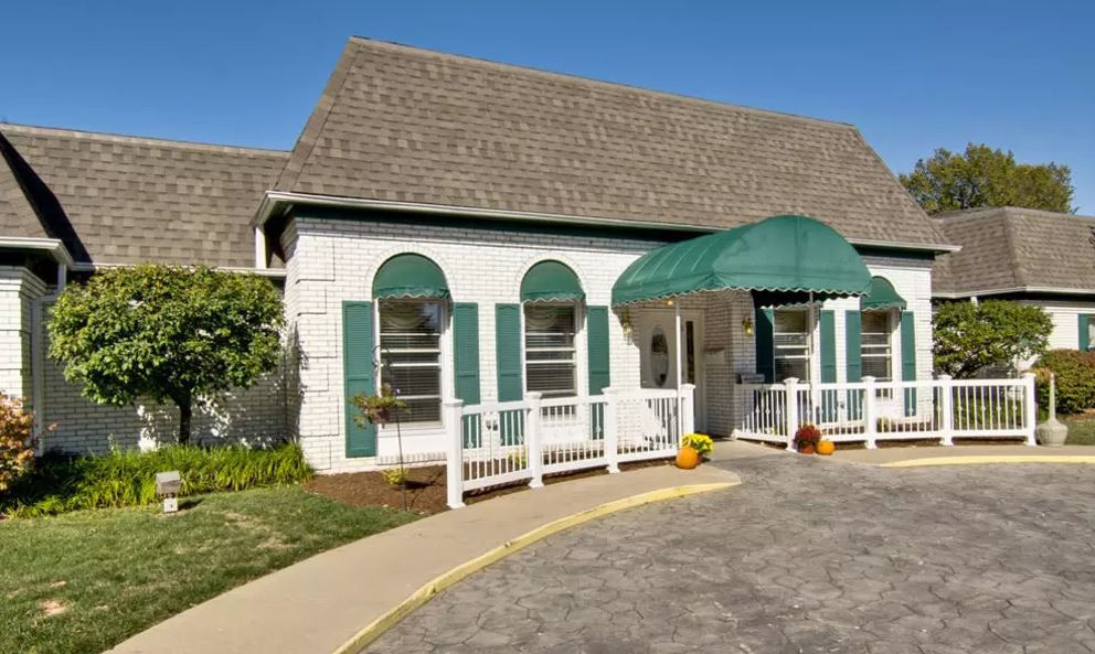A charming building with a green awning and landscaped entrance.