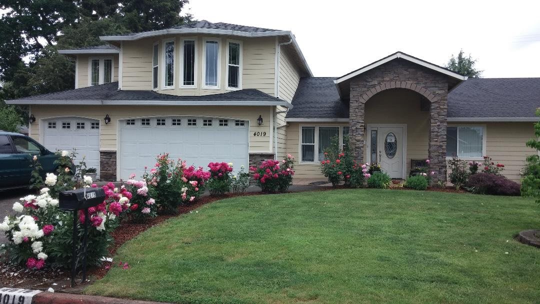 A two-story suburban house with a well-maintained front yard and colorful flowers.