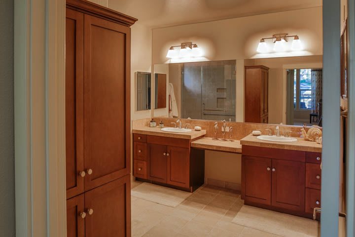 A spacious bathroom with double sinks, wooden cabinets, and large mirrors.