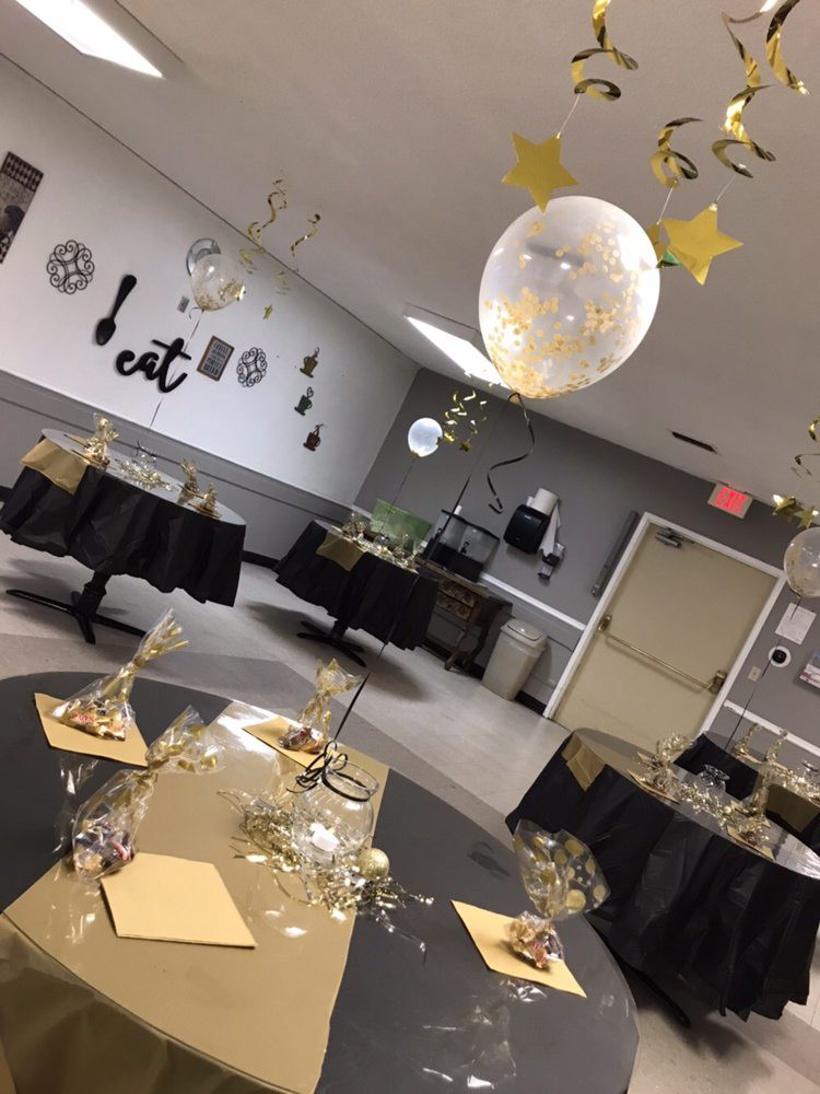 A decorated indoor venue with tables set up for a party, featuring balloons and festive decorations.