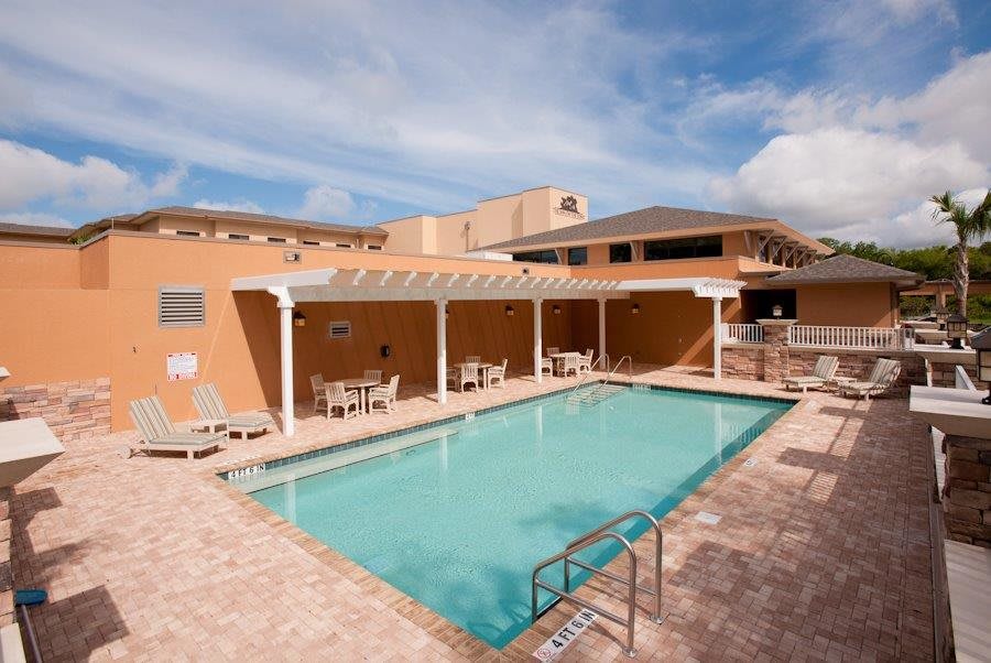 An inviting outdoor swimming pool area with chairs and a patio, perfect for relaxation on a sunny day.