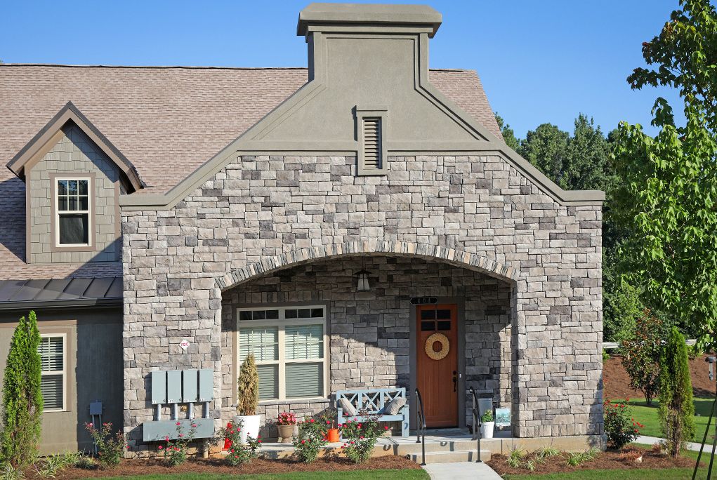A charming stone-faced house with a welcoming front porch and decorative wreath on the door.