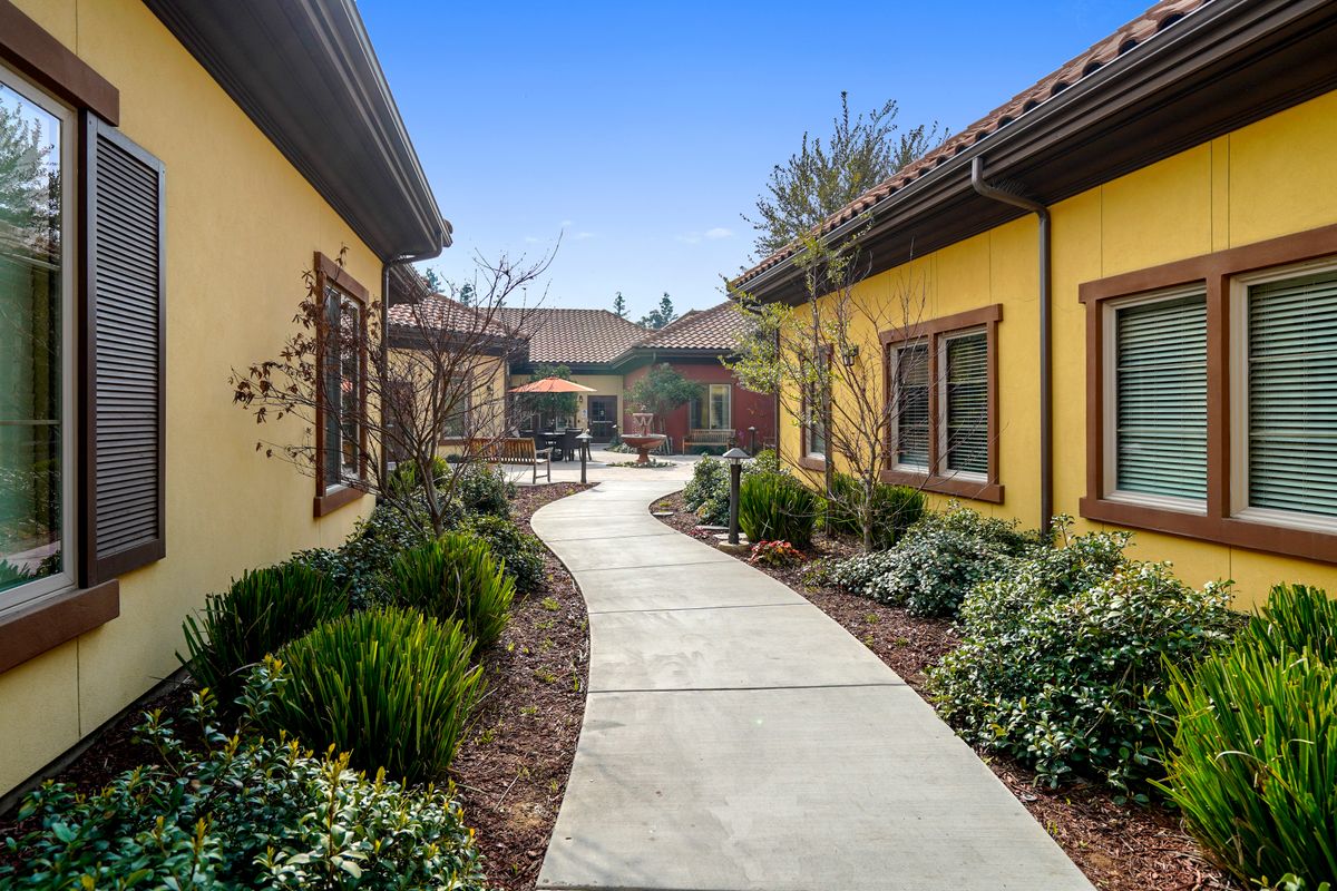 A scenic pathway between buildings surrounded by well-maintained gardens.