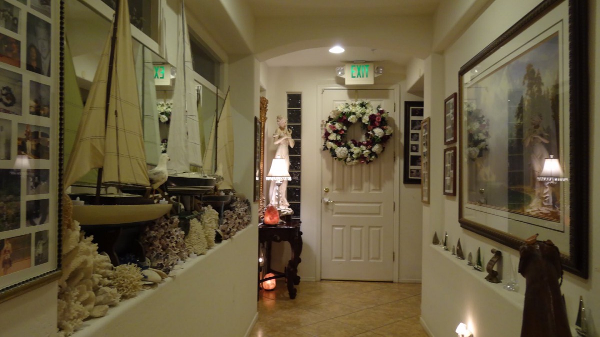 A cozy hallway with nautical decorations, featuring a large wreath on the door and a lamp on a side table.