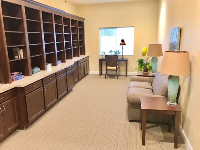 A cozy home office with a desk, shelves, and a sofa.