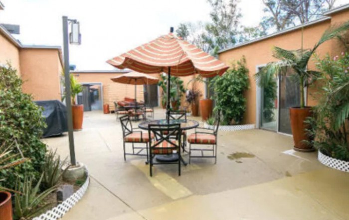 An inviting outdoor patio area with a table and chairs under an umbrella.