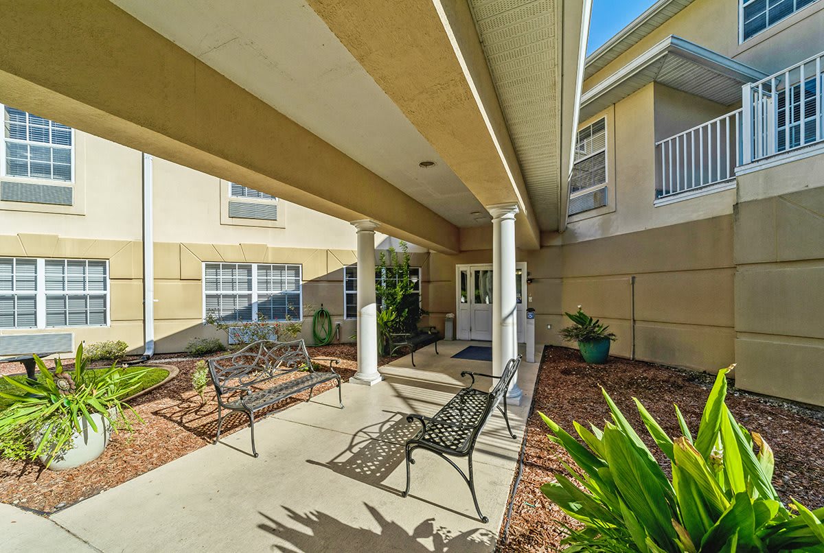 A covered outdoor walkway with benches and landscaped garden area.