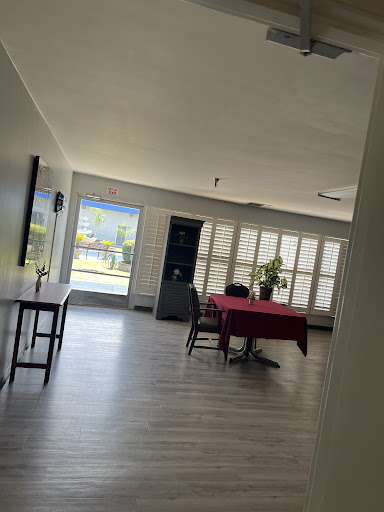 A bright and airy dining space featuring a red tablecloth, stylish chairs, and ample natural light from large windows.