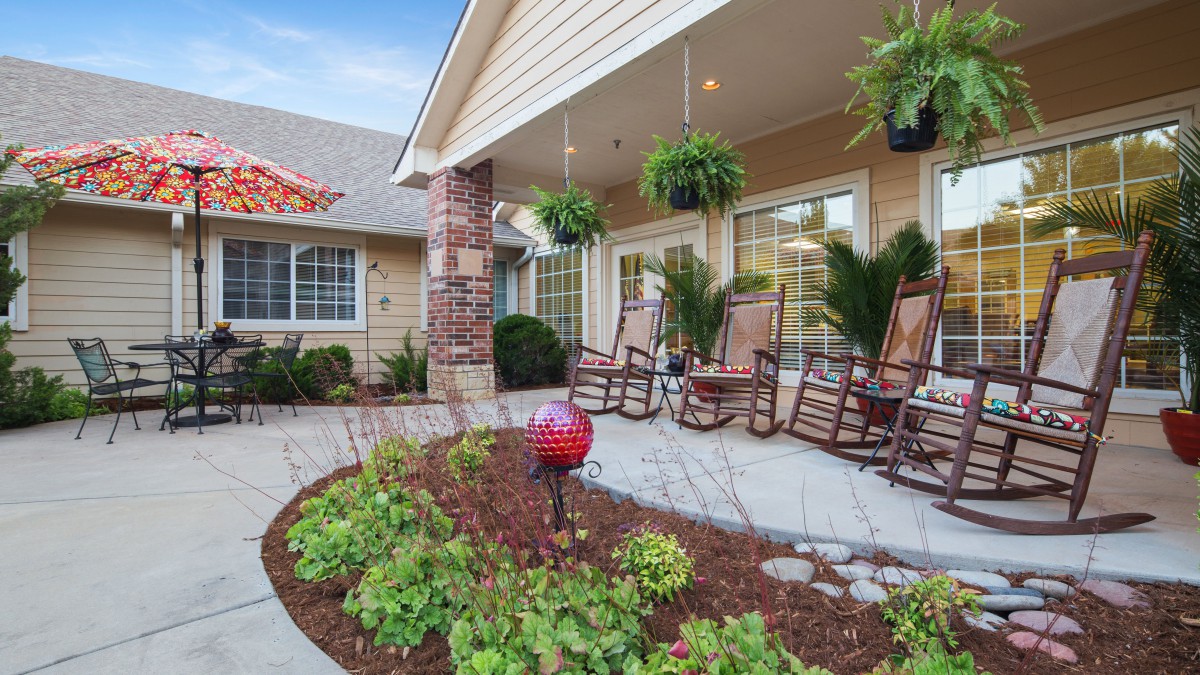 A cozy porch with rocking chairs and lush greenery, inviting relaxation.
