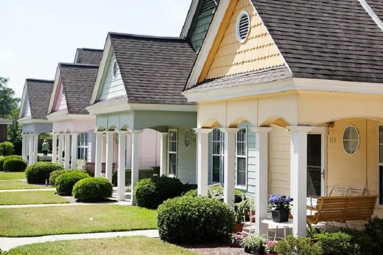 A row of colorful suburban homes with well-maintained lawns.