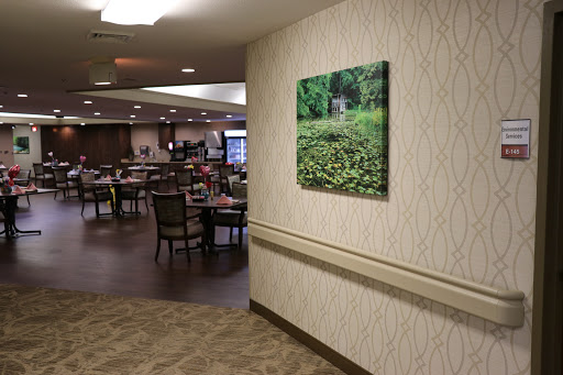 A tranquil wall art depicting a lush green landscape, enhancing the inviting atmosphere of the dining area.