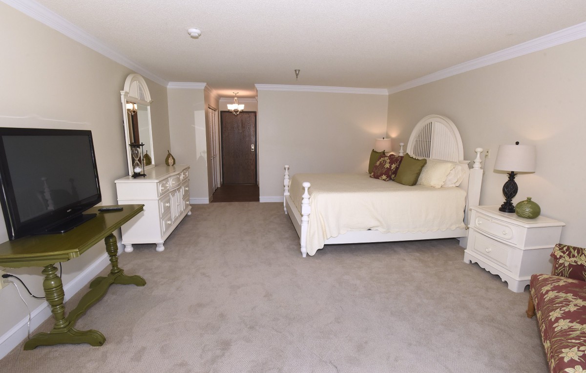 A spacious bedroom with elegant white furniture and neutral decor.