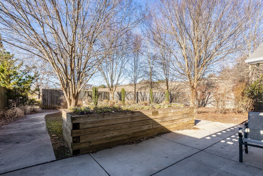 A serene outdoor garden with wooden planters and a paved pathway on a sunny day.