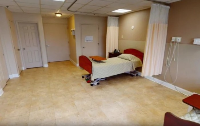 A clean hospital room featuring a single bed and privacy curtains.