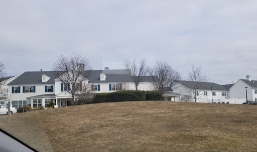 A spacious residential house set against a cloudy sky, surrounded by bare trees and dry grass.
