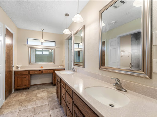 A spacious and modern bathroom featuring double vanities, ample lighting, and stylish mirrors.