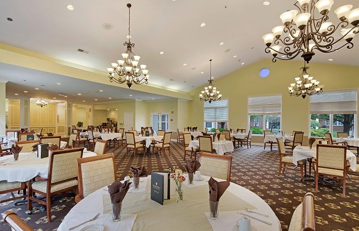 An elegant dining room with chandeliers, well-set tables, and comfortable seating.