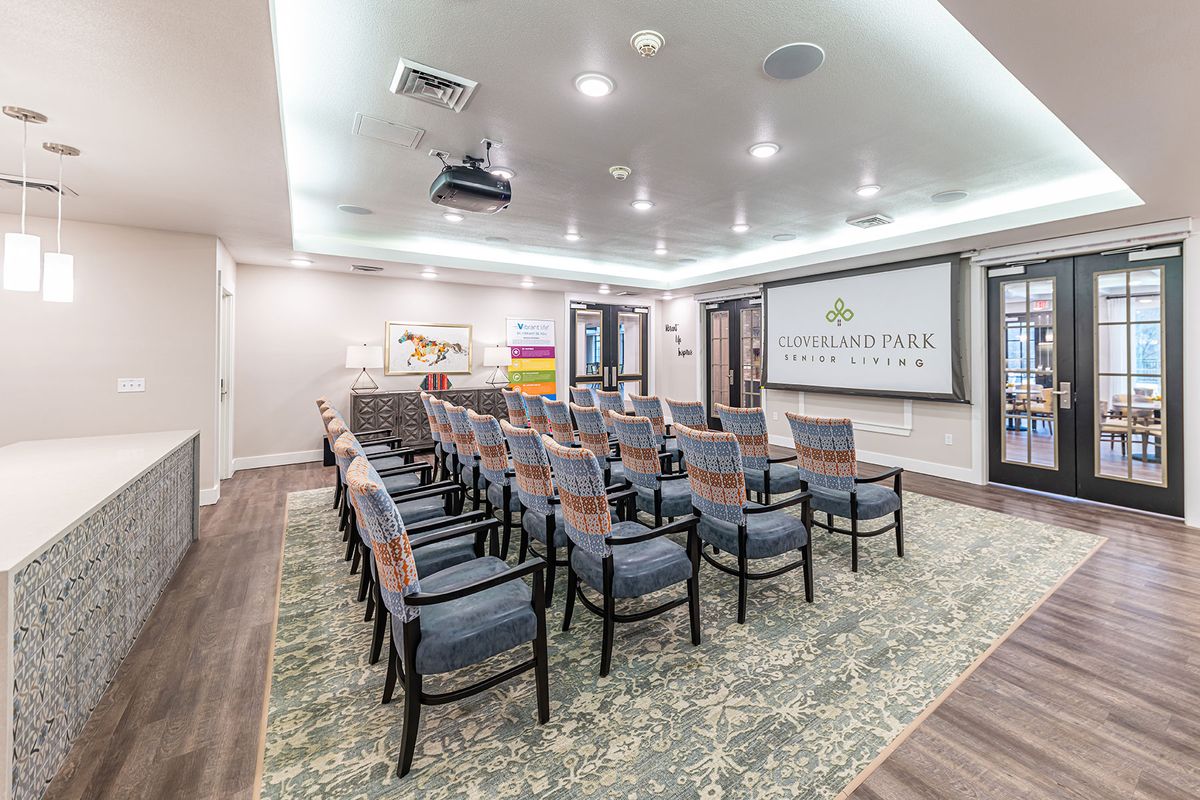 A well-lit conference room with arranged seating and a projector screen.