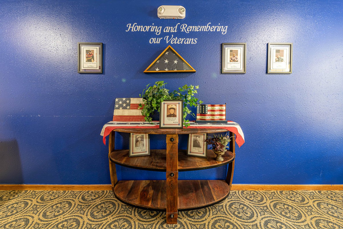 A decorated table honoring and remembering veterans, featuring a folded American flag and framed photos.