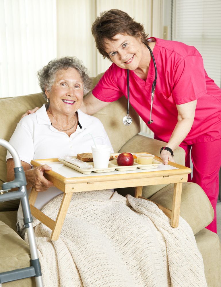 A caregiver assists an elderly woman with her meal at home.