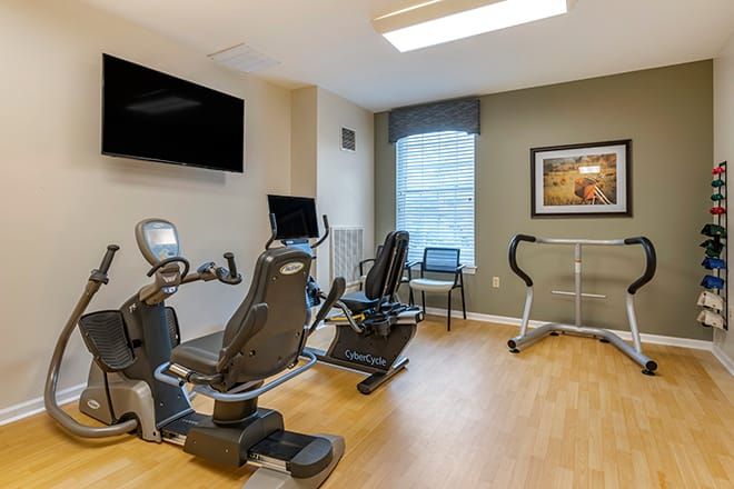 A modern exercise room with stationary bikes and a TV on the wall.