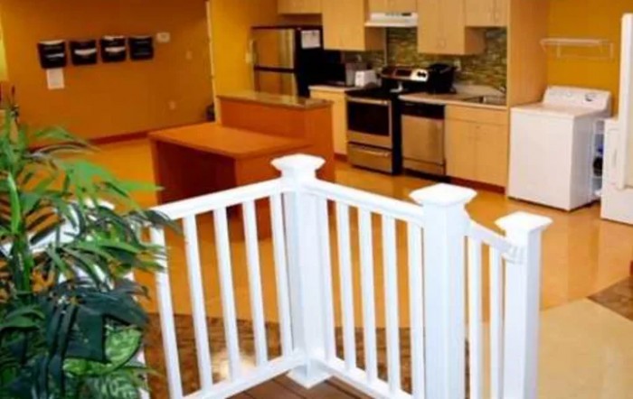 A modern kitchen with appliances and a small white fence partition.