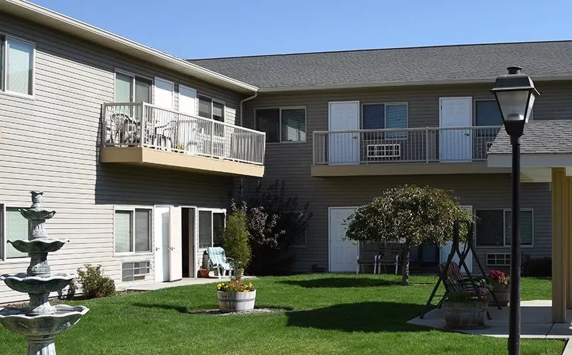 Exterior view of a residential apartment building with balconies and a well-maintained lawn.