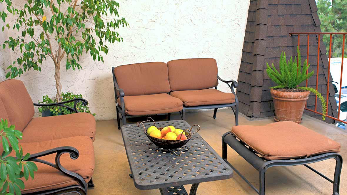 A cozy outdoor patio with cushioned seating and a coffee table adorned with a fruit bowl.