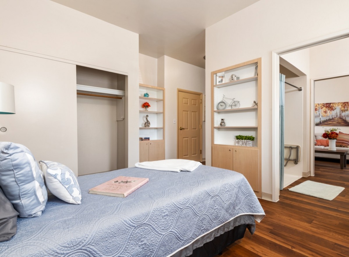 A minimalist bedroom featuring a neatly made bed and built-in shelves for decor.