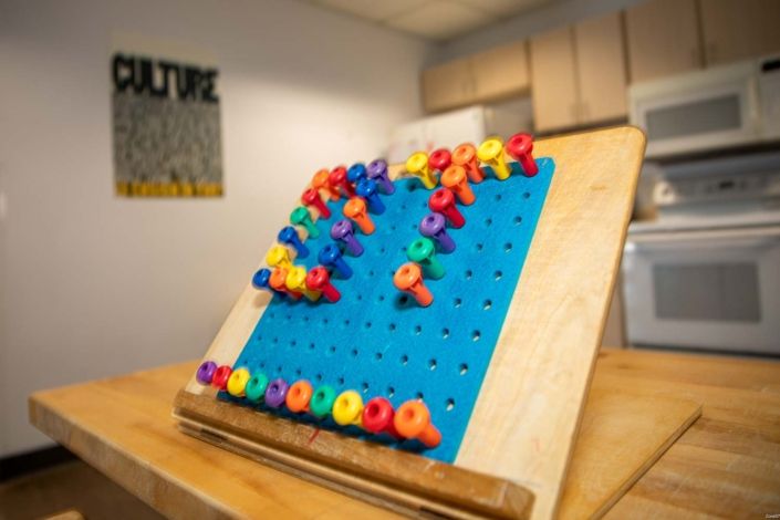 A colorful pegboard with plastic pegs arranged in a pattern.