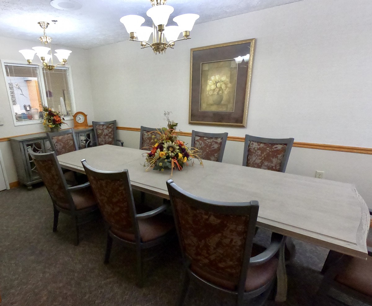 Elegant dining room with a long table, ornate chairs, and chandeliers.