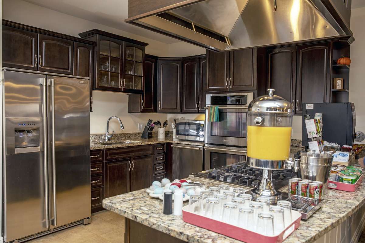 A modern kitchen featuring stainless steel appliances, granite countertops, and a juice dispenser.