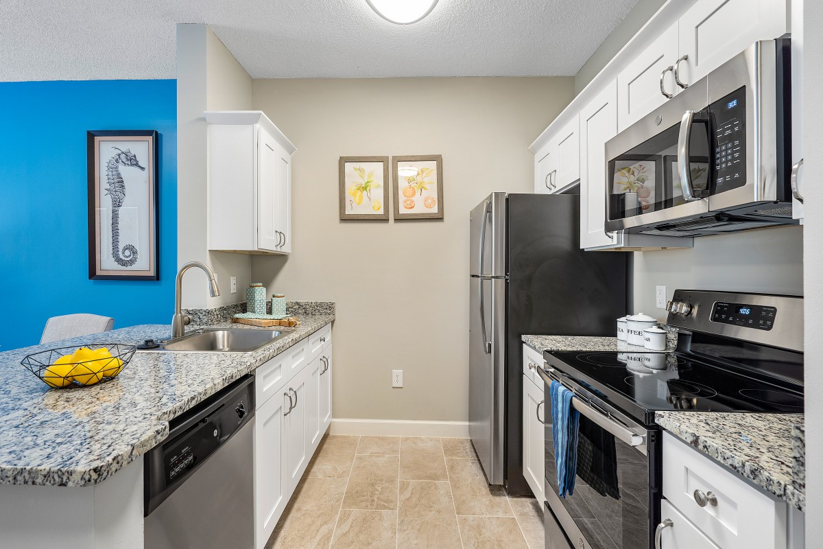 A modern kitchen with white cabinets and stainless steel appliances.