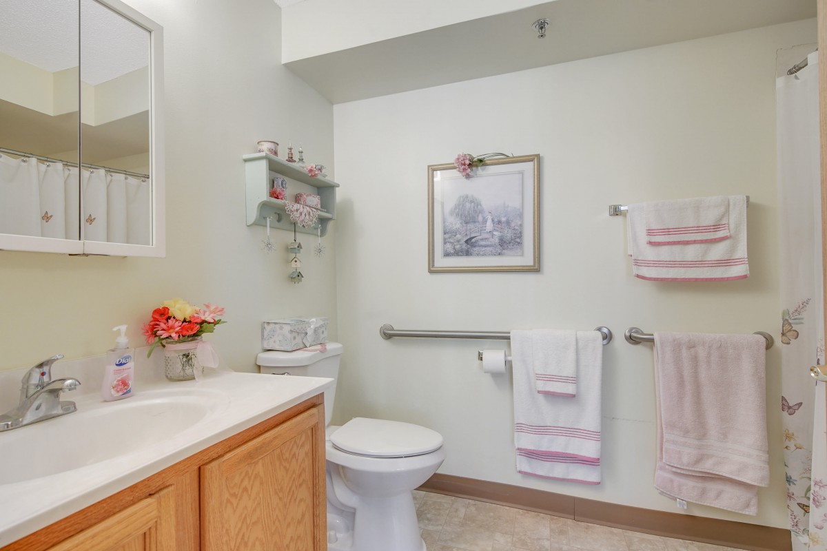 A clean and neatly arranged bathroom with pastel-colored towels, a toilet, and a sink.