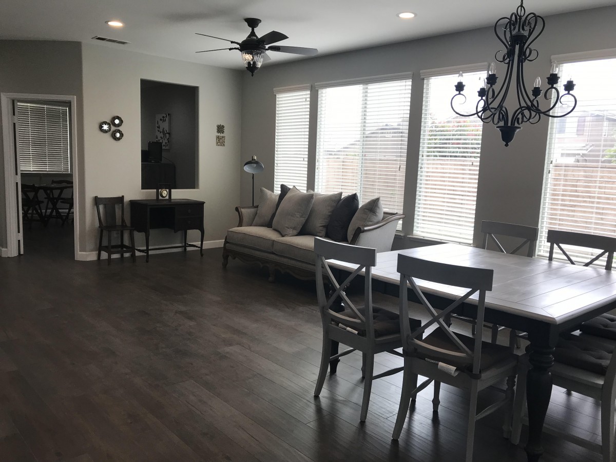 A modern living and dining area with hardwood floors, featuring a comfortable sofa, a large dining table, and a chandelier.