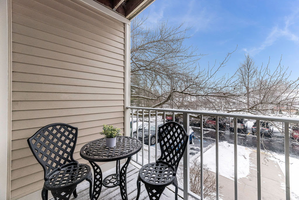 A cozy balcony with a small table and chairs, overlooking a snowy landscape.