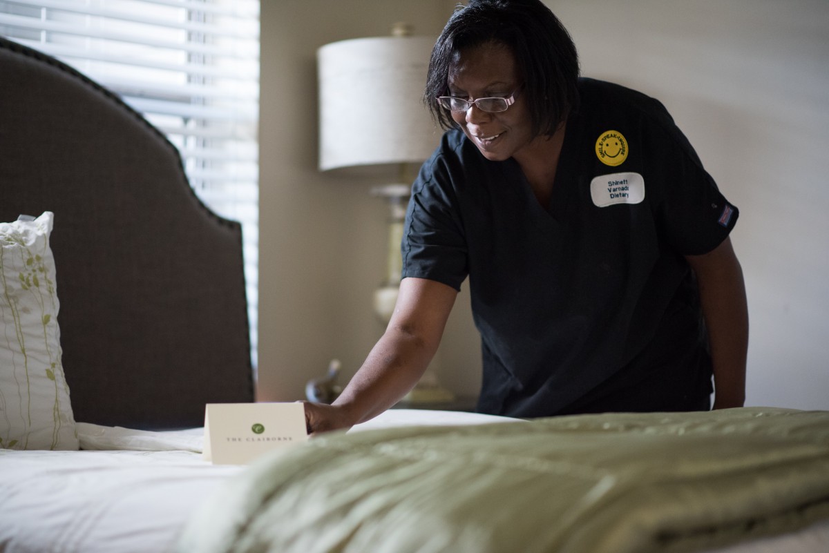 A housekeeping staff member tidying up a hotel room.