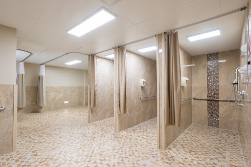 A modern, minimalist shower area featuring multiple stalls with curtains and tiled floors.