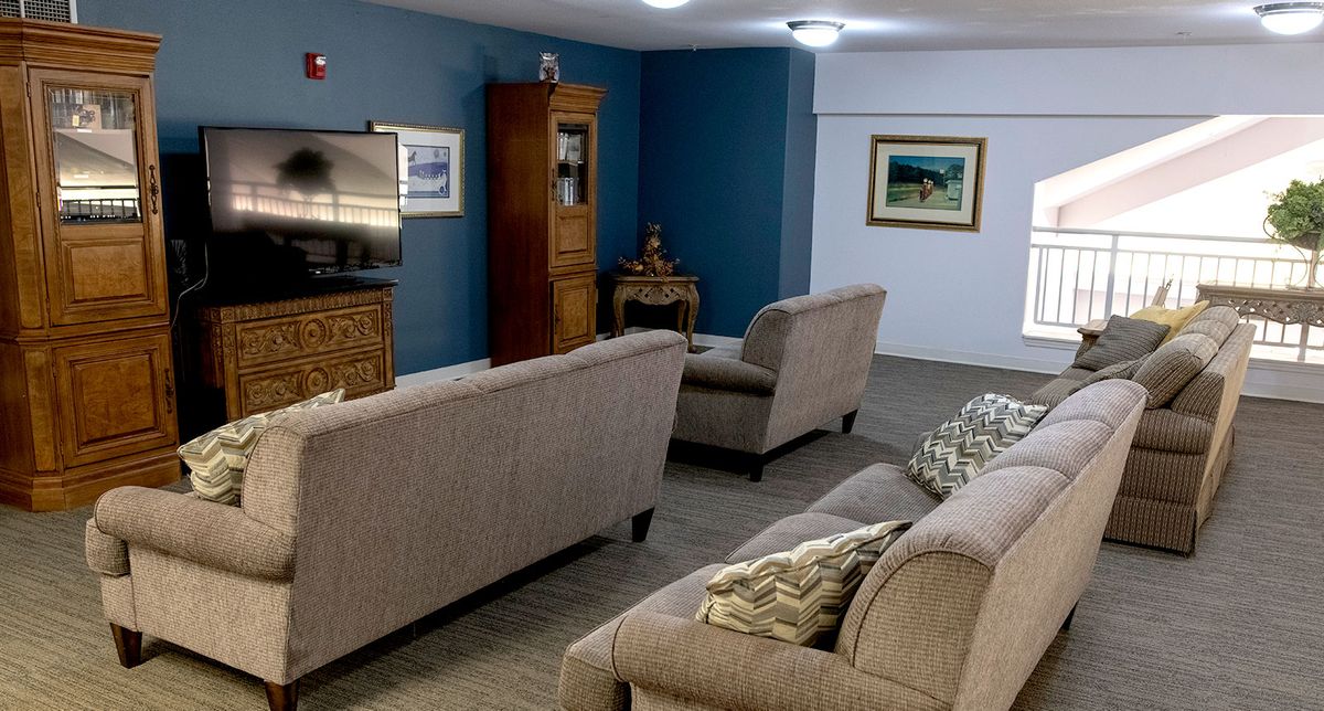 A cozy living room with beige sofas, a television, and artwork on the walls.