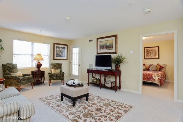A well-decorated living room featuring comfortable seating, a television, and elegant artwork on the walls.
