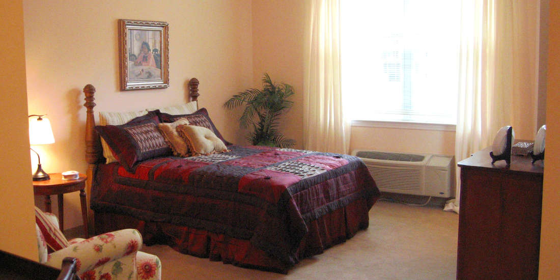 A cozy bedroom with a decorated bed and large window.