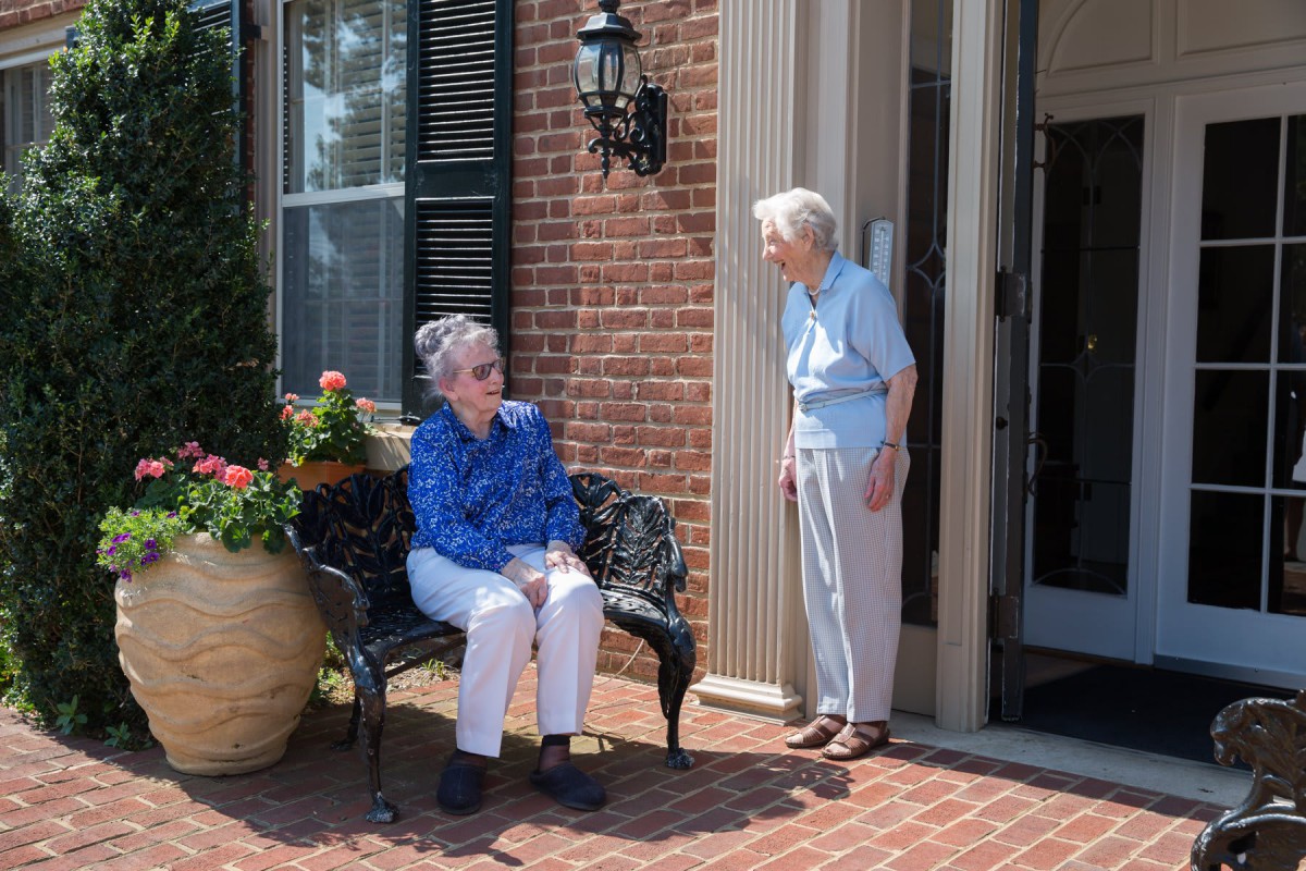 Two elderly women enjoying a conversation on a porch.