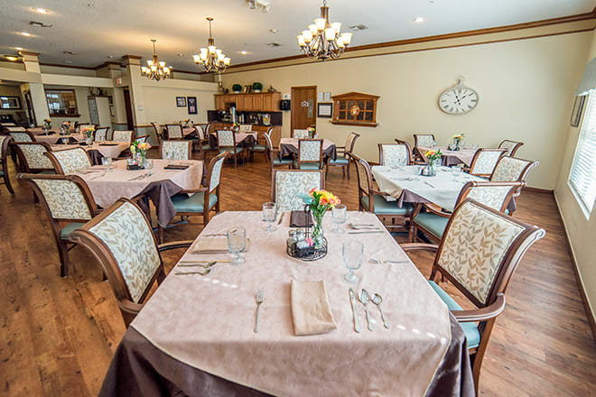 Elegant dining room with neatly arranged tables and chairs, featuring classic decor and chandeliers.