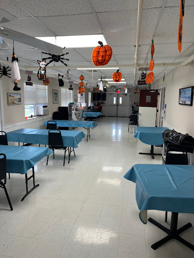 An empty dining area decorated for Halloween, featuring blue tables and festive decorations hanging from the ceiling.