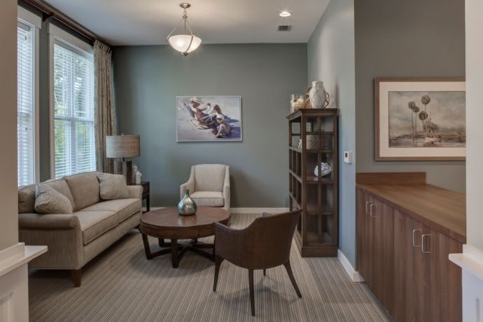 A cozy living room with a sofa, armchair, coffee table, and bookshelf.
