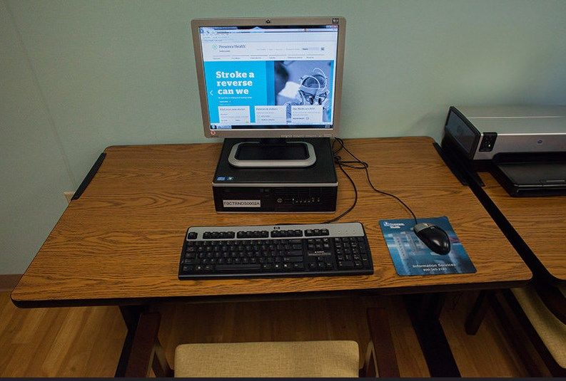 A desktop computer setup on a wooden table, including a monitor, keyboard, and mouse.