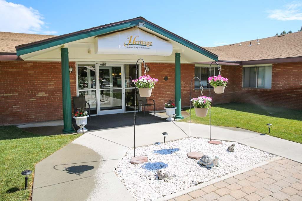 Front entrance of a building with hanging flower baskets and a landscaped garden.